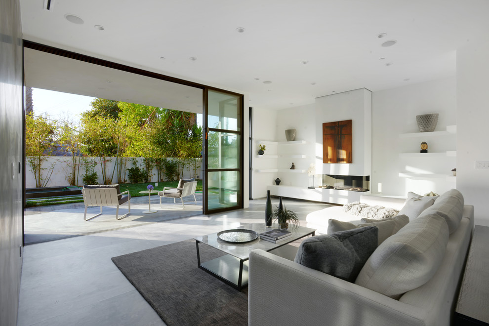 Example of a large trendy formal and open concept concrete floor living room design in Los Angeles with white walls, a standard fireplace, a plaster fireplace and no tv