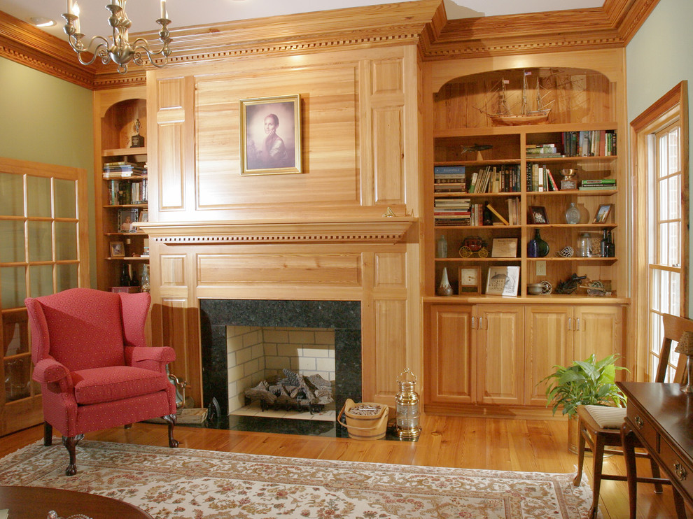 На фото: изолированная гостиная комната среднего размера в классическом стиле с с книжными шкафами и полками, зелеными стенами, паркетным полом среднего тона, стандартным камином, фасадом камина из дерева и коричневым полом без телевизора с