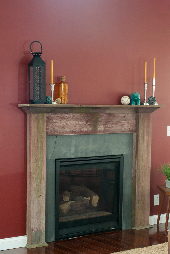 シカゴにあるお手頃価格の中くらいなラスティックスタイルのおしゃれなリビング (赤い壁、無垢フローリング、標準型暖炉、コンクリートの暖炉まわり、テレビなし、茶色い床) の写真