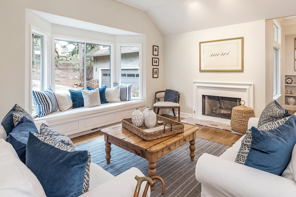 Fernseherloses Landhaus Wohnzimmer mit beiger Wandfarbe, braunem Holzboden, Kamin, Kaminumrandung aus Stein und braunem Boden in Sonstige