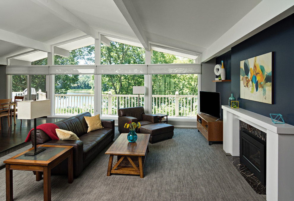 Пример оригинального дизайна: огромная открытая гостиная комната в современном стиле с синими стенами, ковровым покрытием, стандартным камином, отдельно стоящим телевизором, фасадом камина из камня и серым полом