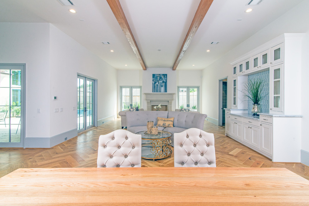 Repräsentatives, Offenes, Großes Klassisches Wohnzimmer mit weißer Wandfarbe, hellem Holzboden, Kamin und verputzter Kaminumrandung in Houston