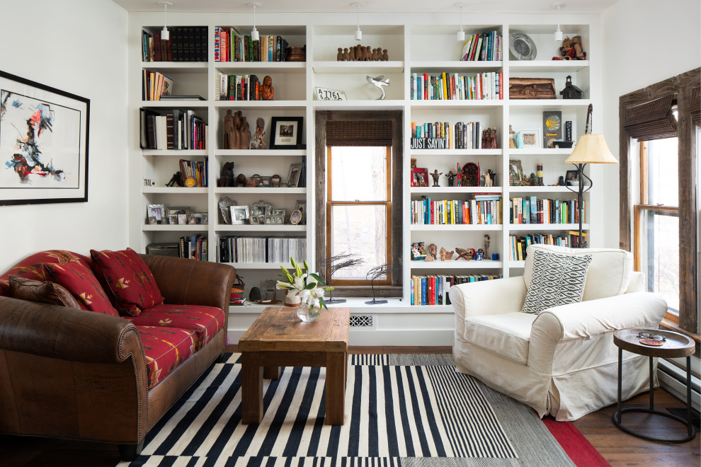Exemple d'un salon sud-ouest américain de taille moyenne et fermé avec une bibliothèque ou un coin lecture, un mur blanc, un sol en bois brun, aucun téléviseur et un sol marron.