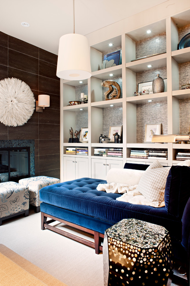 На фото: гостиная комната в современном стиле с с книжными шкафами и полками и фасадом камина из плитки с
