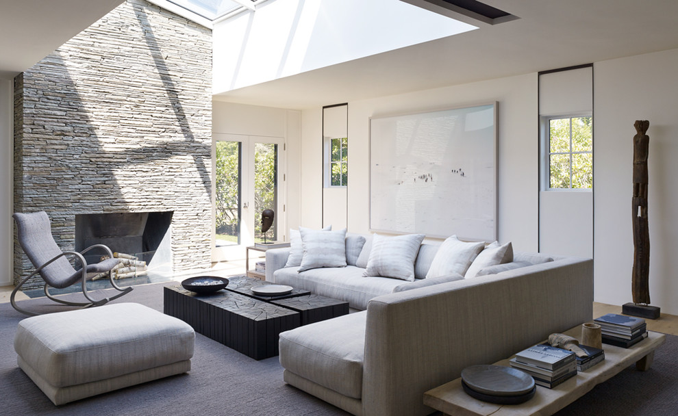 На фото: гостиная комната в стиле модернизм с белыми стенами, стандартным камином и фасадом камина из камня с