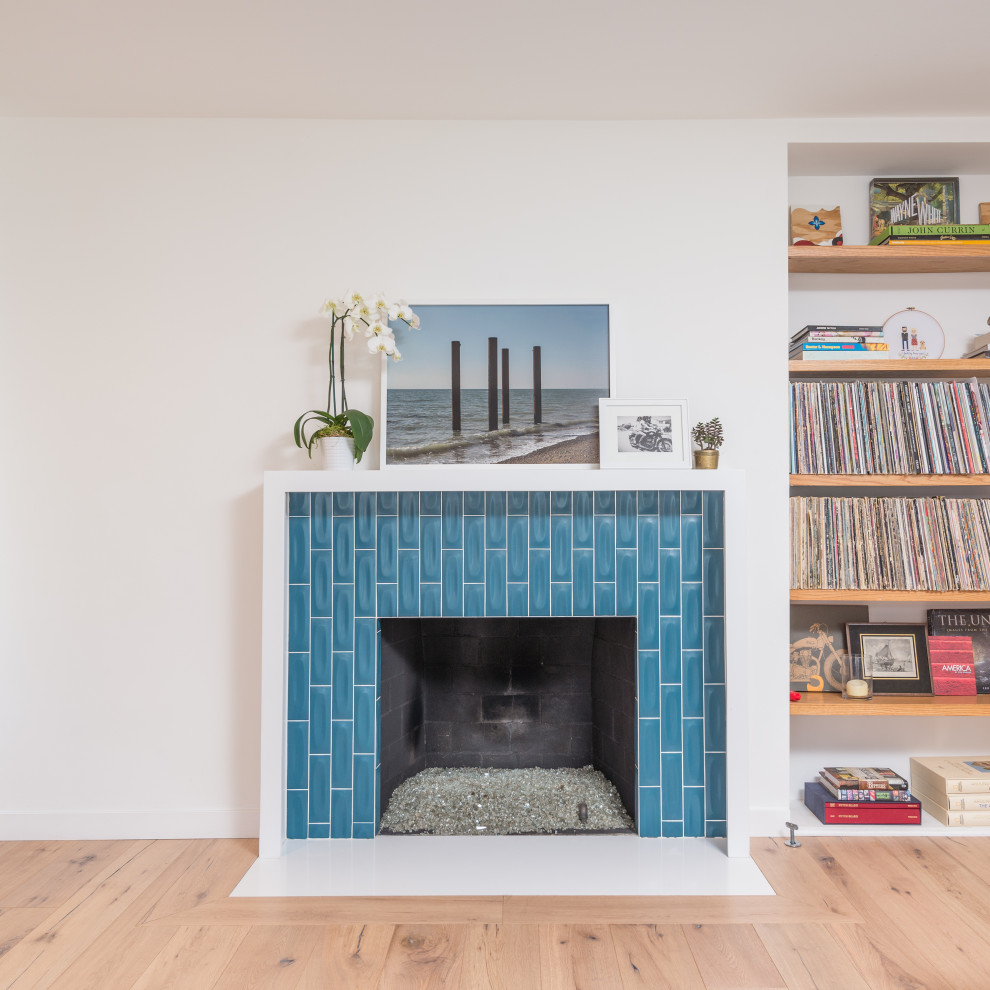 ミッドセンチュリースタイルのおしゃれなリビング (白い壁、淡色無垢フローリング、標準型暖炉、タイルの暖炉まわり) の写真