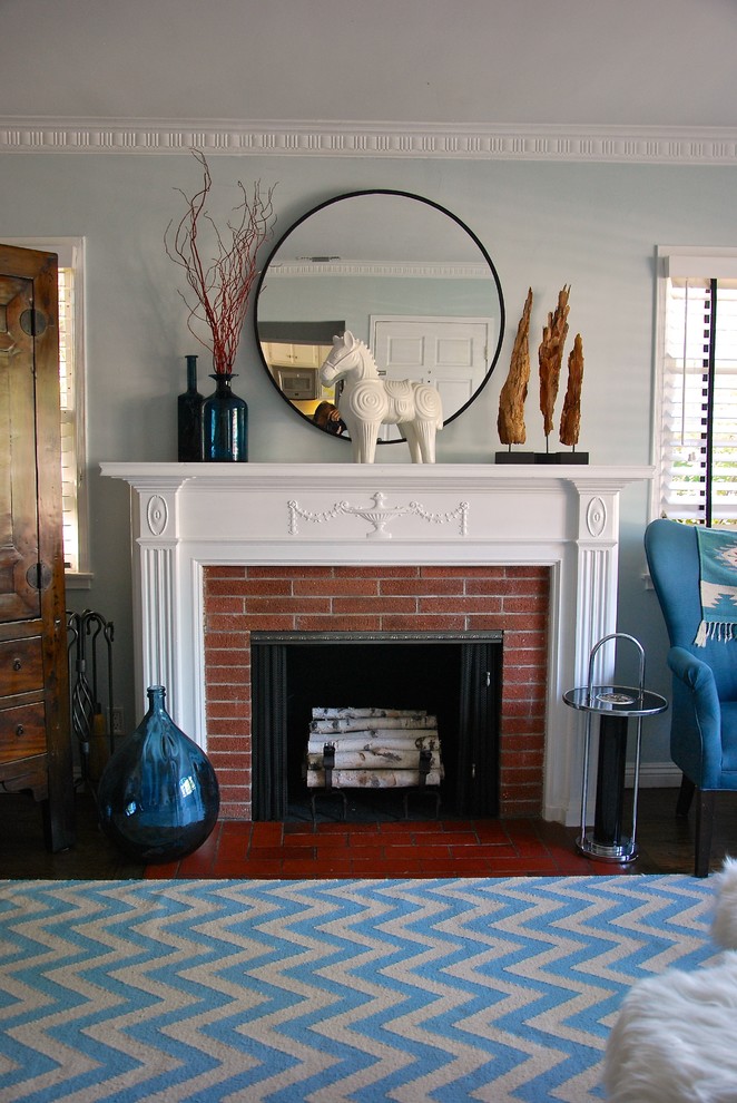 Idée de décoration pour un salon design de taille moyenne et ouvert avec un mur bleu, parquet foncé, une cheminée standard, un manteau de cheminée en brique et un téléviseur dissimulé.