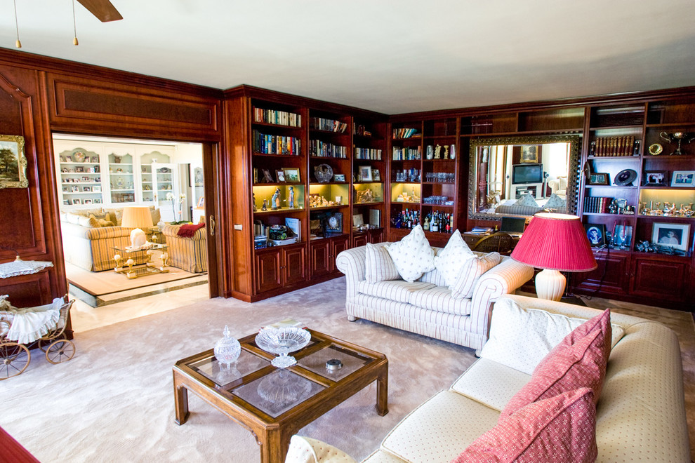 Cette image montre un grand salon méditerranéen ouvert avec une bibliothèque ou un coin lecture et un mur marron.