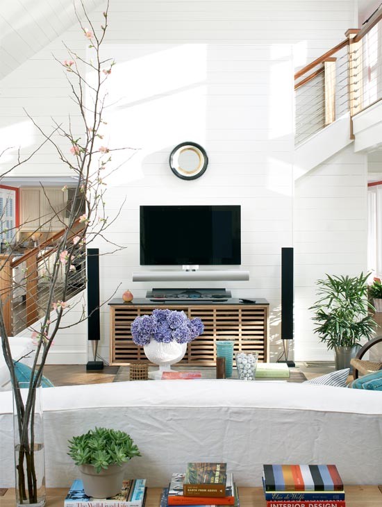 Idées déco pour un grand salon bord de mer ouvert avec un mur blanc, un sol en bois brun et un téléviseur fixé au mur.