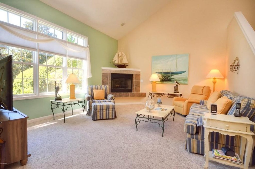 Inspiration for a medium sized beach style open plan living room in Wilmington with green walls, carpet, a corner fireplace, a tiled fireplace surround, a freestanding tv and beige floors.