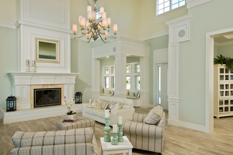 Источник вдохновения для домашнего уюта: большая открытая гостиная комната в классическом стиле с зелеными стенами, стандартным камином, светлым паркетным полом и фасадом камина из плитки