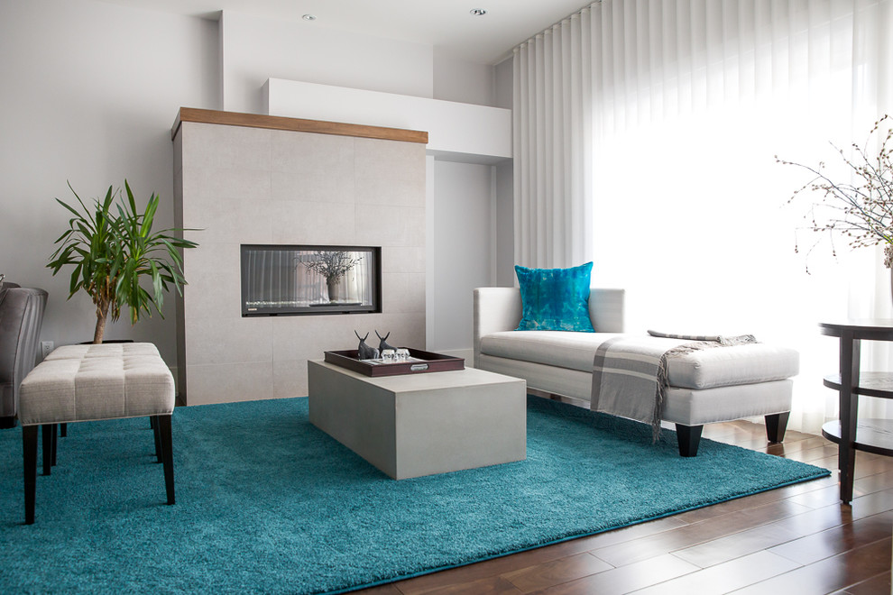 Immagine di un grande soggiorno minimalista aperto con sala formale, pareti grigie, parquet scuro, camino classico, cornice del camino piastrellata e pavimento marrone