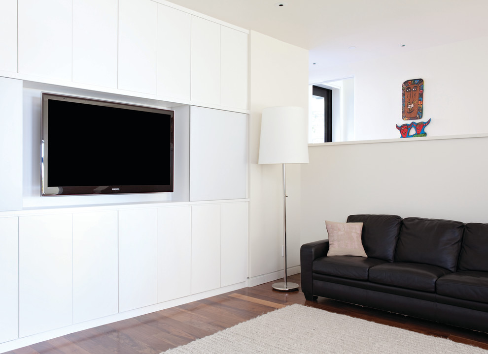 Foto på ett mellanstort funkis allrum med öppen planlösning, med vita väggar, mörkt trägolv och en dold TV