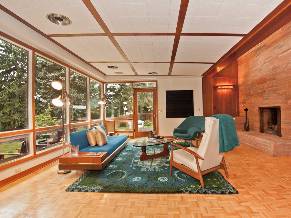 На фото: гостиная комната в стиле ретро с стандартным камином, фасадом камина из камня и синим диваном с