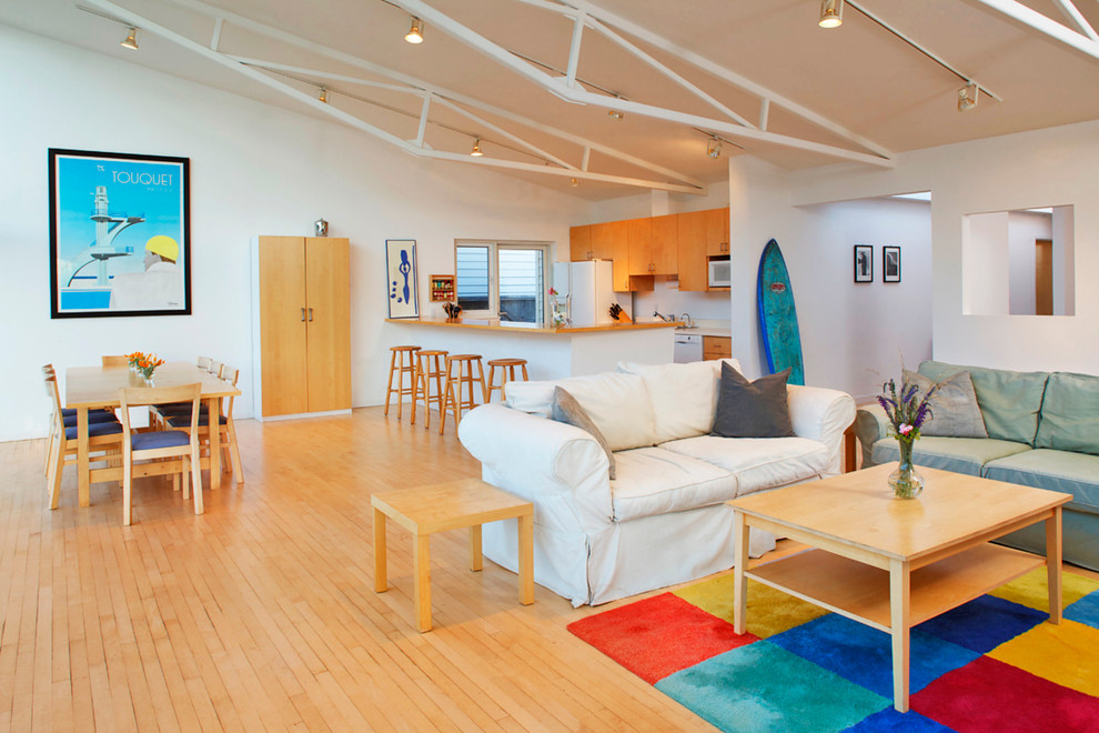 Diseño de salón abierto costero grande con paredes blancas y suelo de madera en tonos medios
