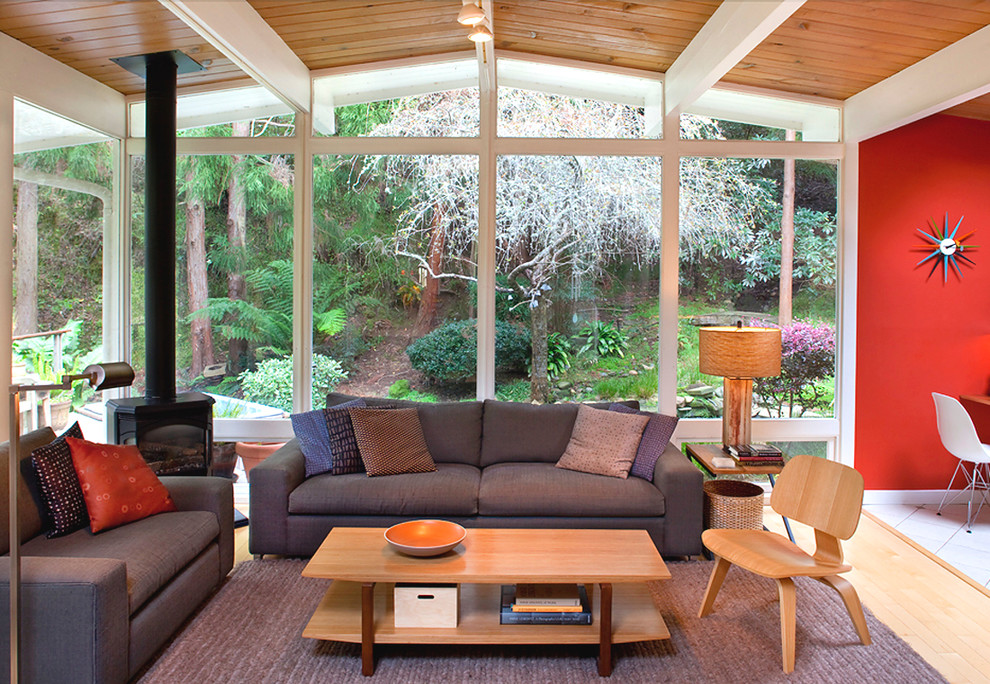 Foto di un soggiorno moderno aperto con pareti rosse, parquet chiaro e stufa a legna