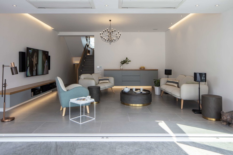 Cette photo montre un salon tendance avec un mur blanc, un téléviseur fixé au mur et un sol gris.