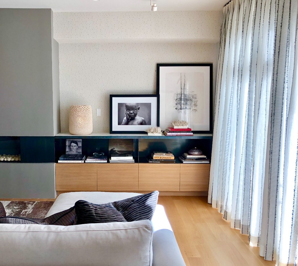 Exemple d'un salon tendance de taille moyenne et ouvert avec un mur beige, parquet clair, un manteau de cheminée en plâtre, un sol beige, une cheminée standard et du papier peint.