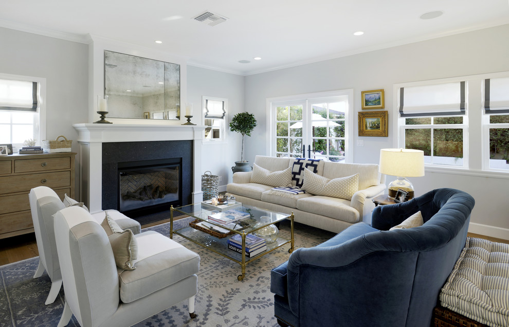 Imagen de salón tradicional con paredes azules, suelo de madera en tonos medios, todas las chimeneas y televisor retractable