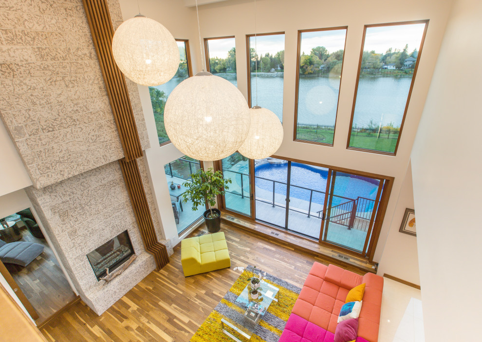 На фото: открытая гостиная комната в стиле модернизм с белыми стенами, паркетным полом среднего тона, стандартным камином, фасадом камина из камня и коричневым полом без телевизора с