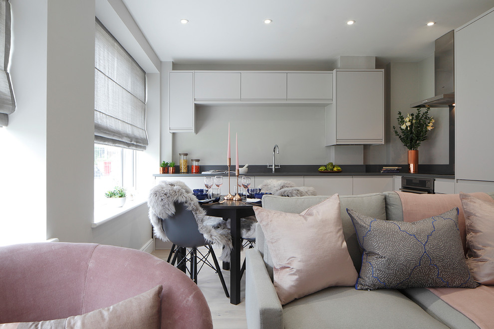 This is an example of a small contemporary open plan living room in London with grey walls, light hardwood flooring, no fireplace, a freestanding tv and grey floors.