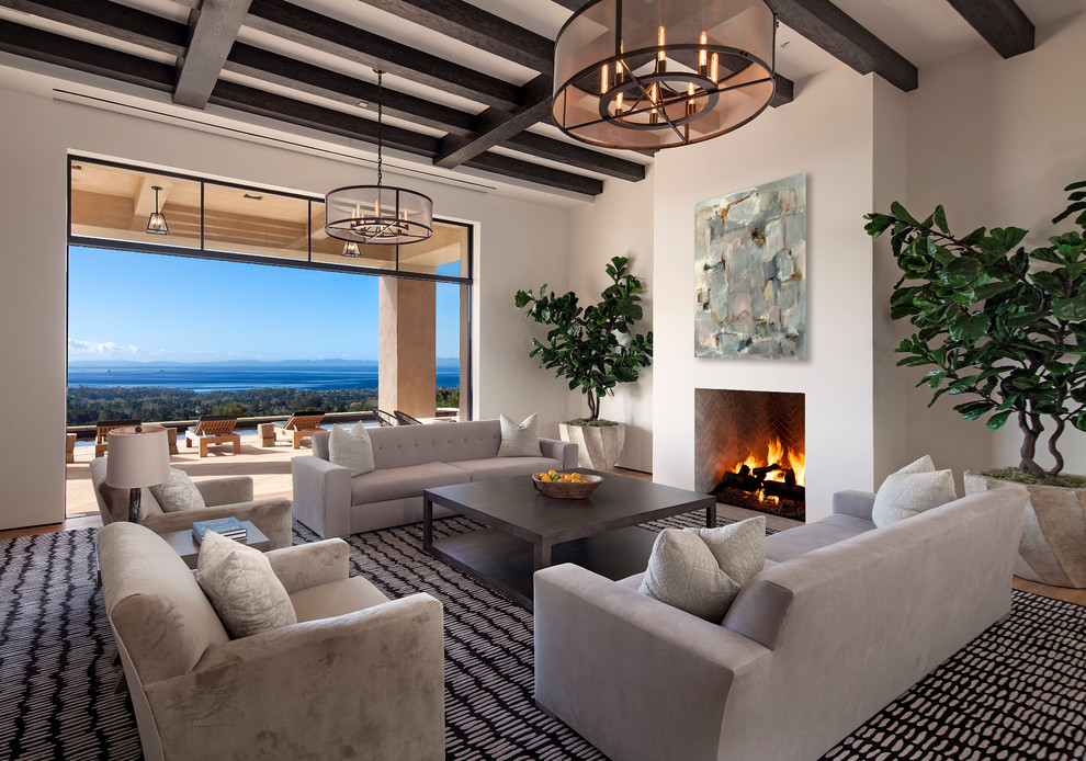Large trendy open concept medium tone wood floor living room photo in Santa Barbara with beige walls, a standard fireplace, a plaster fireplace and no tv