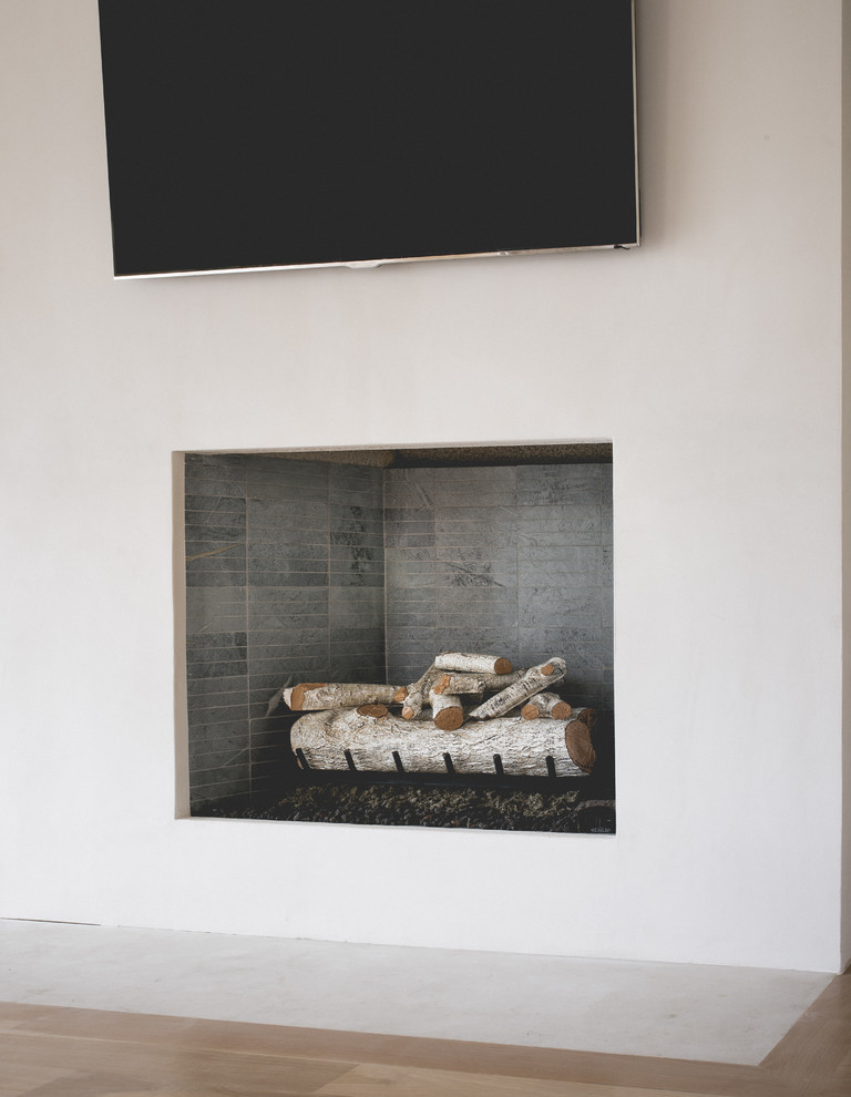 Foto di un grande soggiorno contemporaneo aperto con sala formale, pareti beige, parquet chiaro, camino classico, cornice del camino in intonaco e TV a parete