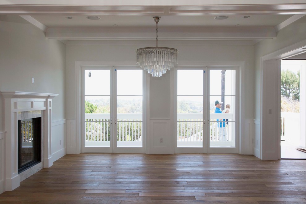 Großes, Repräsentatives, Offenes Maritimes Wohnzimmer mit weißer Wandfarbe, braunem Holzboden, Kamin und Kaminumrandung aus Stein in Los Angeles