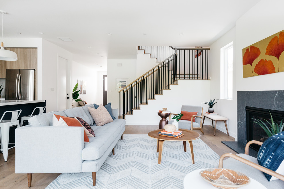 Immagine di un soggiorno design con pareti bianche, pavimento in legno massello medio, camino classico e pavimento marrone