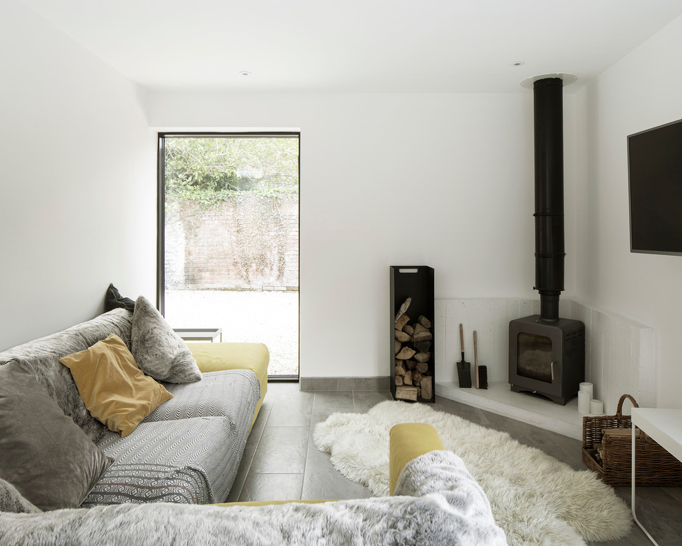 Photo of a small contemporary enclosed living room in Hampshire with a reading nook, white walls, ceramic flooring, a wood burning stove, a concrete fireplace surround, a wall mounted tv and grey floors.