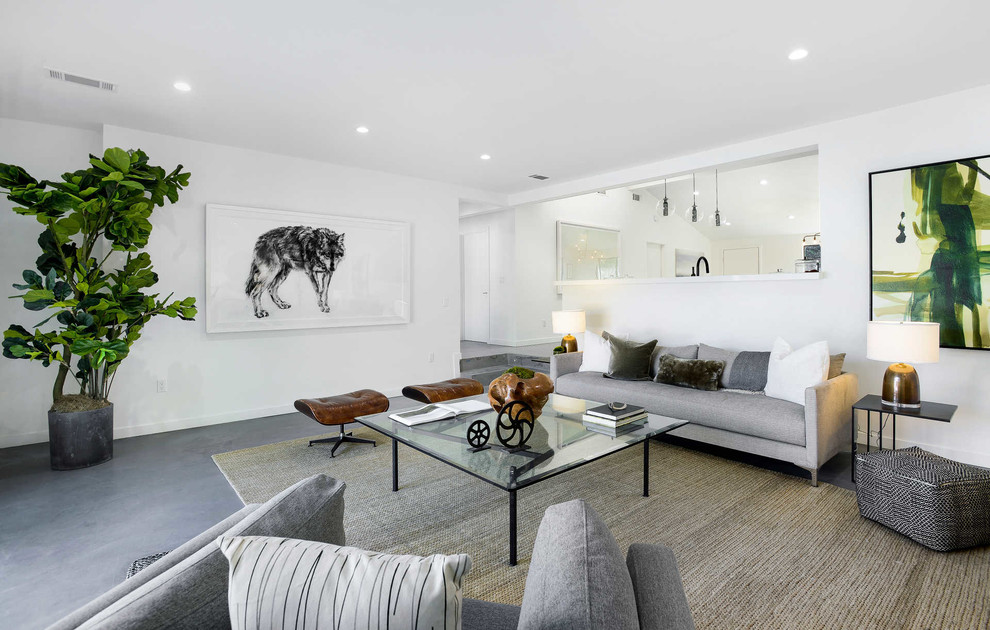 This is an example of a contemporary open plan living room in Los Angeles with white walls and grey floors.
