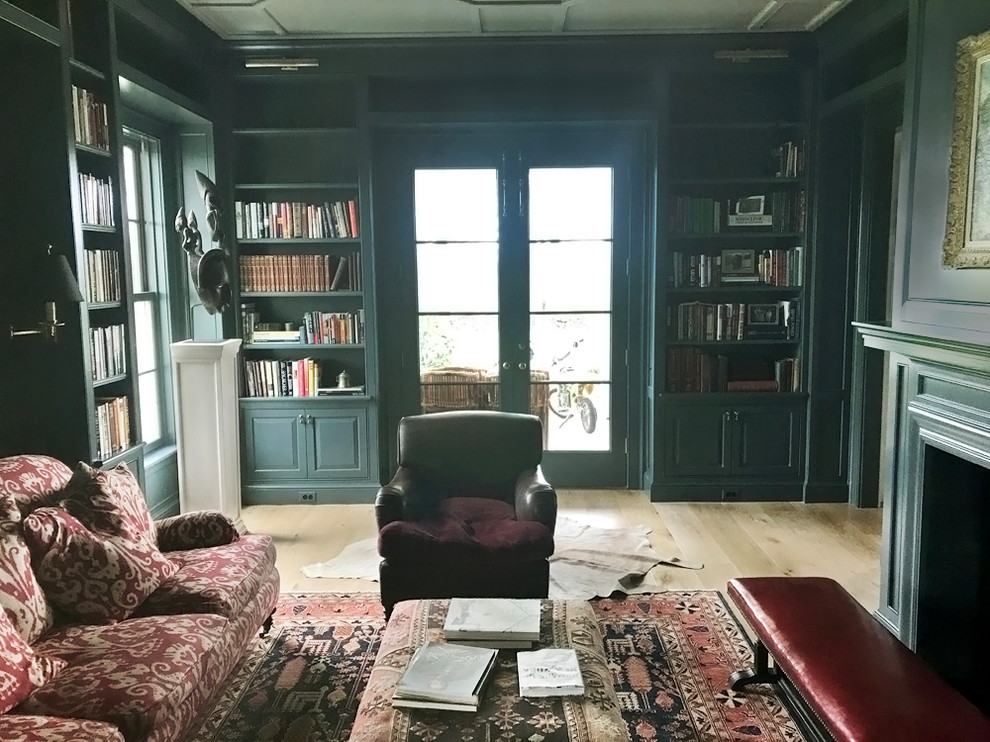 Foto på ett mellanstort vintage separat vardagsrum, med ett bibliotek, blå väggar, en standard öppen spis, en spiselkrans i sten och en dold TV