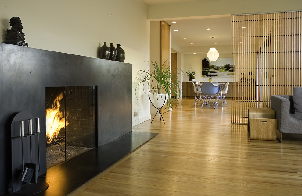 Стильный дизайн: гостиная комната в стиле модернизм с бежевыми стенами, стандартным камином и фасадом камина из металла - последний тренд