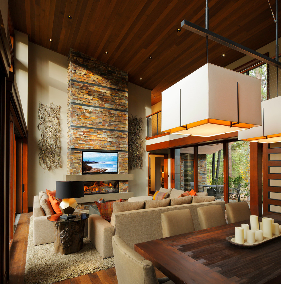 Foto de salón abierto rural de tamaño medio con paredes beige, suelo de madera en tonos medios, chimenea lineal, marco de chimenea de piedra y televisor colgado en la pared