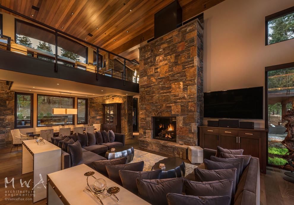 Design ideas for a large rustic open plan living room in Other with beige walls, dark hardwood flooring, a standard fireplace, a stone fireplace surround, a wall mounted tv and brown floors.