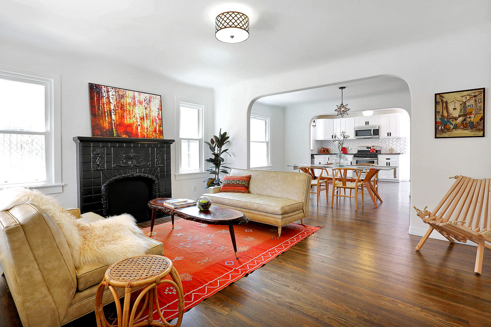 Cette photo montre un salon éclectique avec un mur blanc, un sol en bois brun, une cheminée standard et un manteau de cheminée en brique.
