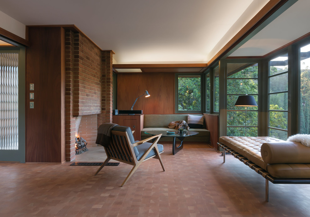 Foto di un soggiorno moderno di medie dimensioni con pavimento in legno massello medio, camino classico e cornice del camino in mattoni