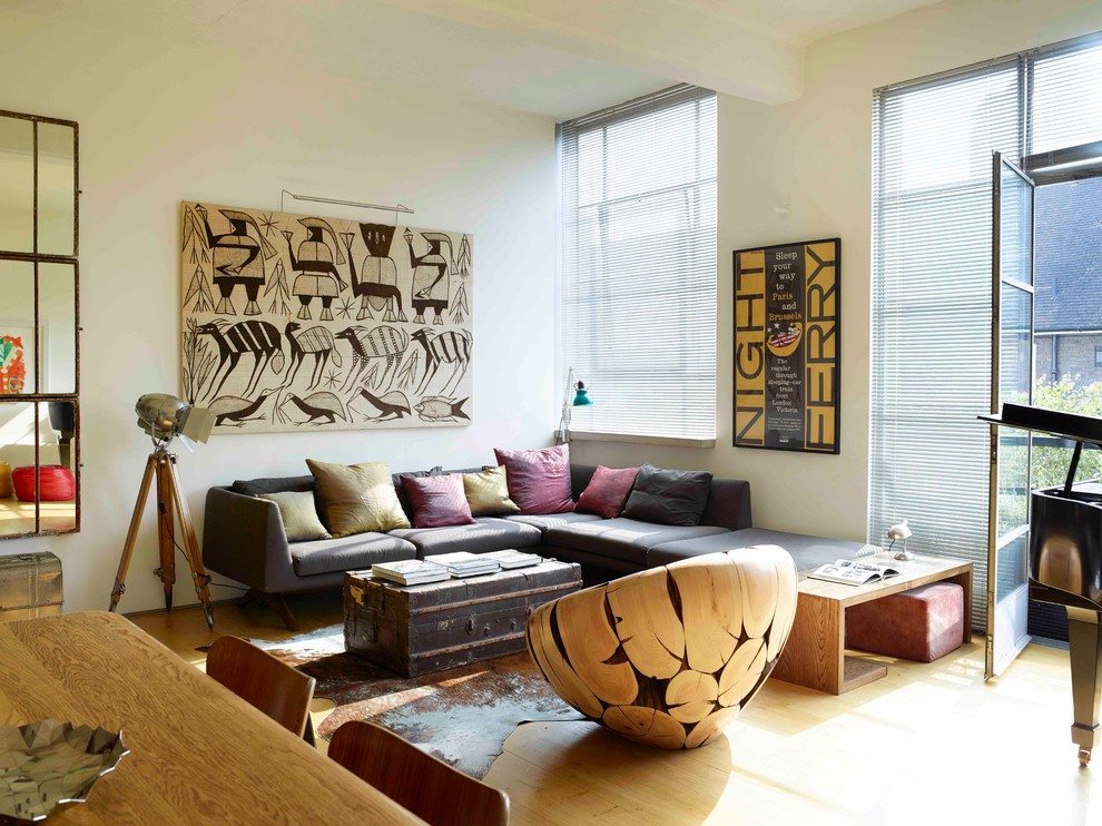 Inspiration for a huge eclectic open concept light wood floor living room remodel in London with white walls