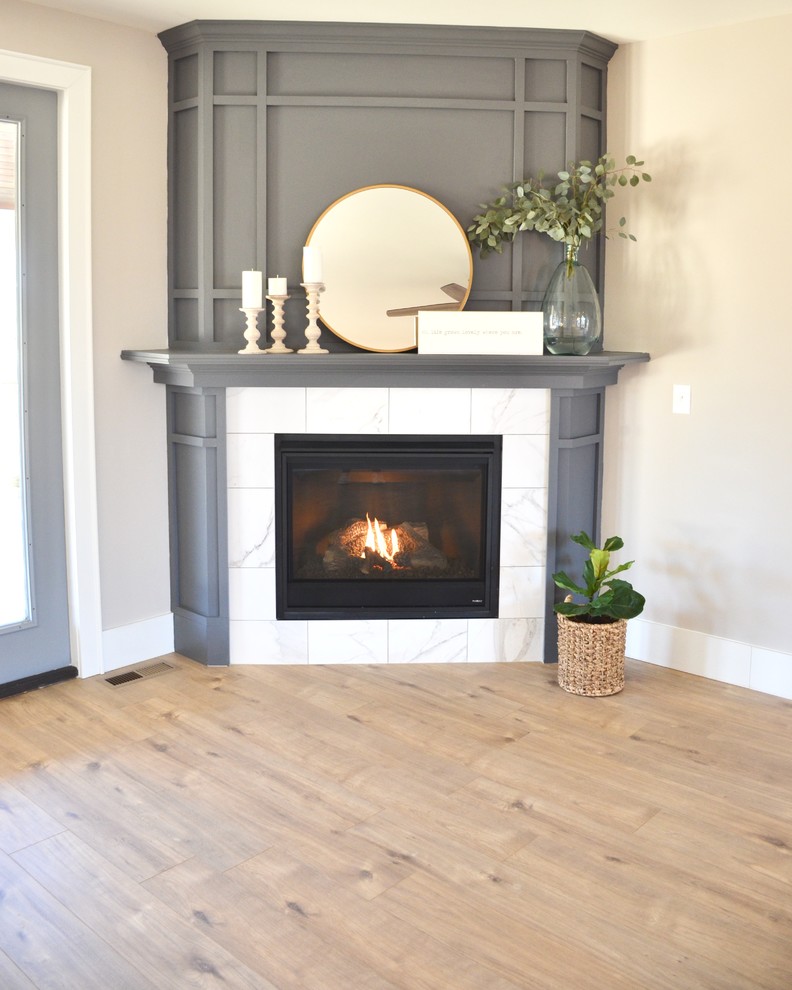 Offenes Country Wohnzimmer mit grauer Wandfarbe, braunem Holzboden, Eckkamin und Kaminumrandung aus Holz in Sonstige