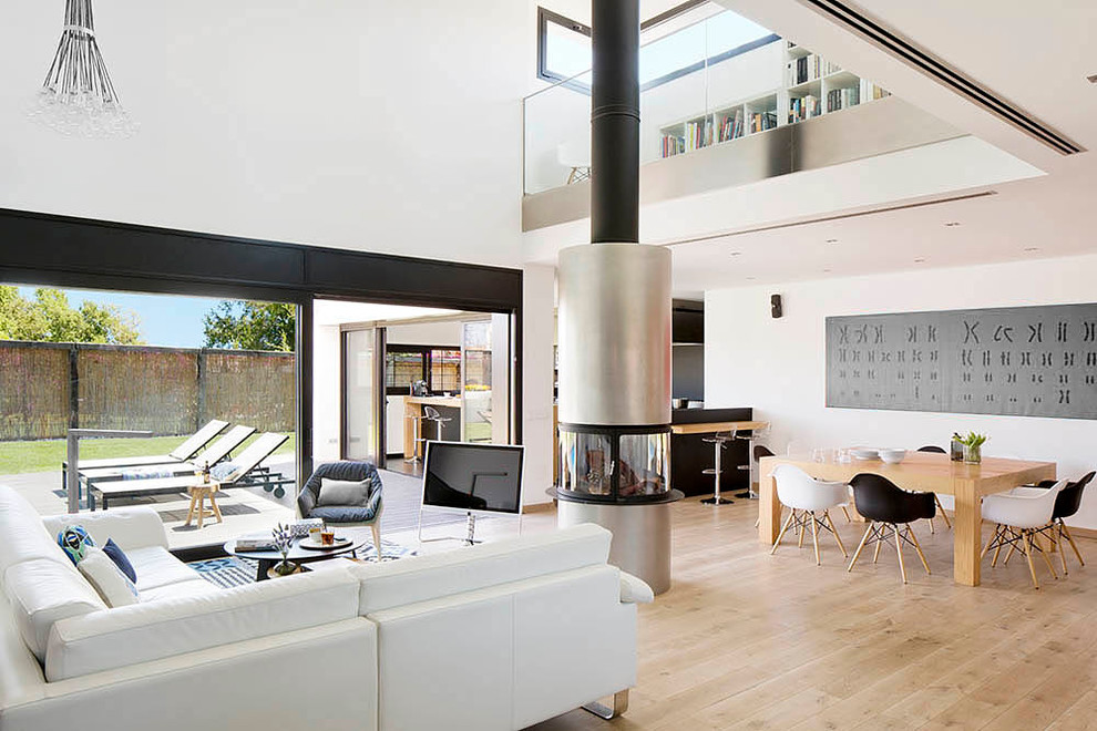 Idee per un grande soggiorno moderno aperto con sala formale, pareti bianche, parquet chiaro, camino sospeso e TV autoportante
