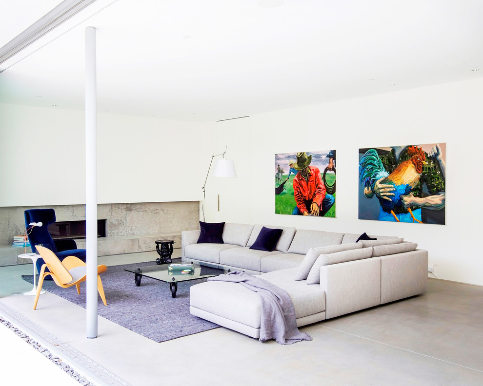 Aménagement d'un salon moderne ouvert avec un mur blanc, sol en béton ciré, une cheminée ribbon et un sol gris.