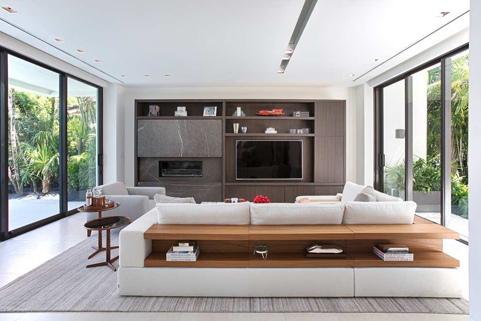 Стильный дизайн: гостиная комната в современном стиле с белыми стенами, горизонтальным камином, телевизором на стене и белым полом - последний тренд