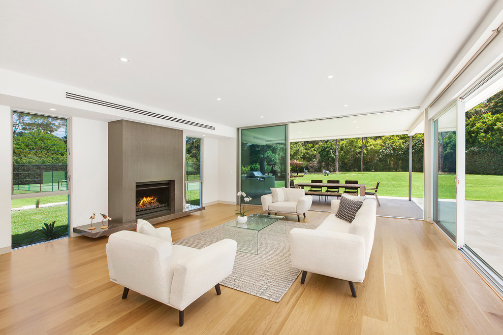 Example of a large minimalist open concept and formal light wood floor living room design in Central Coast with a standard fireplace and white walls