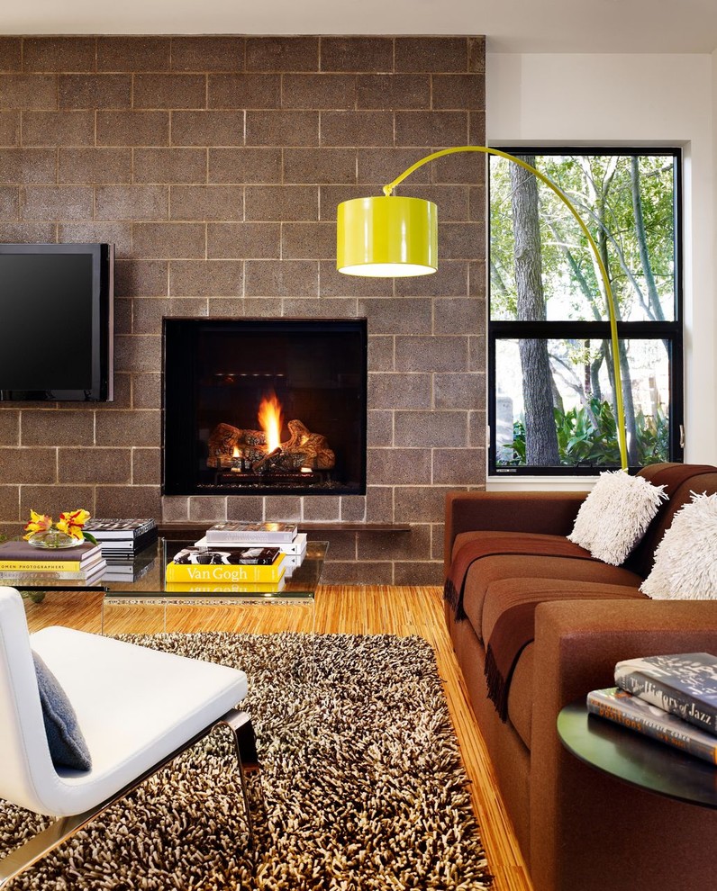 オースティンにあるモダンスタイルのおしゃれなリビング (標準型暖炉、壁掛け型テレビ、茶色いソファ) の写真