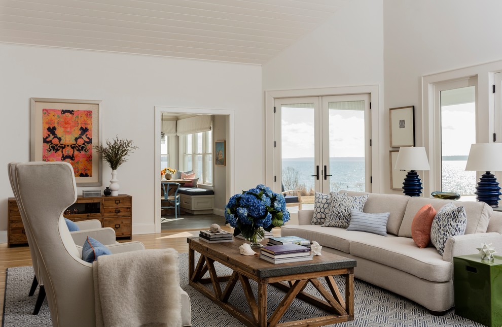 На фото: большая открытая гостиная комната в морском стиле с белыми стенами, паркетным полом среднего тона, стандартным камином, фасадом камина из камня и синим полом без телевизора
