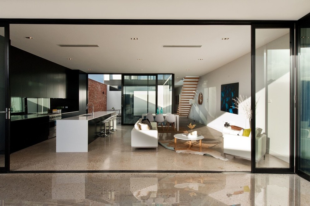 Источник вдохновения для домашнего уюта: большая открытая гостиная комната в современном стиле с белыми стенами, бетонным полом и телевизором на стене