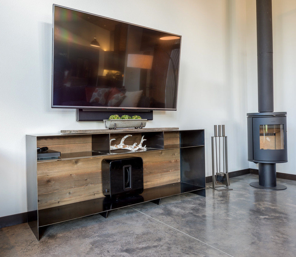 Esempio di un soggiorno minimalista di medie dimensioni e aperto con angolo bar, pareti gialle, pavimento in cemento, stufa a legna, TV a parete e pavimento beige