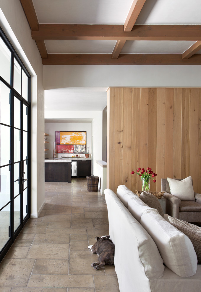 На фото: гостиная комната в средиземноморском стиле с белыми стенами, полом из травертина и серым полом с