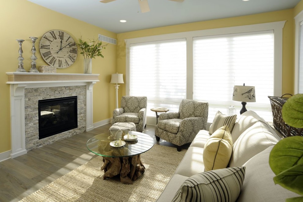 На фото: открытая гостиная комната в классическом стиле с стандартным камином, желтыми стенами, полом из винила, фасадом камина из каменной кладки и серым полом с