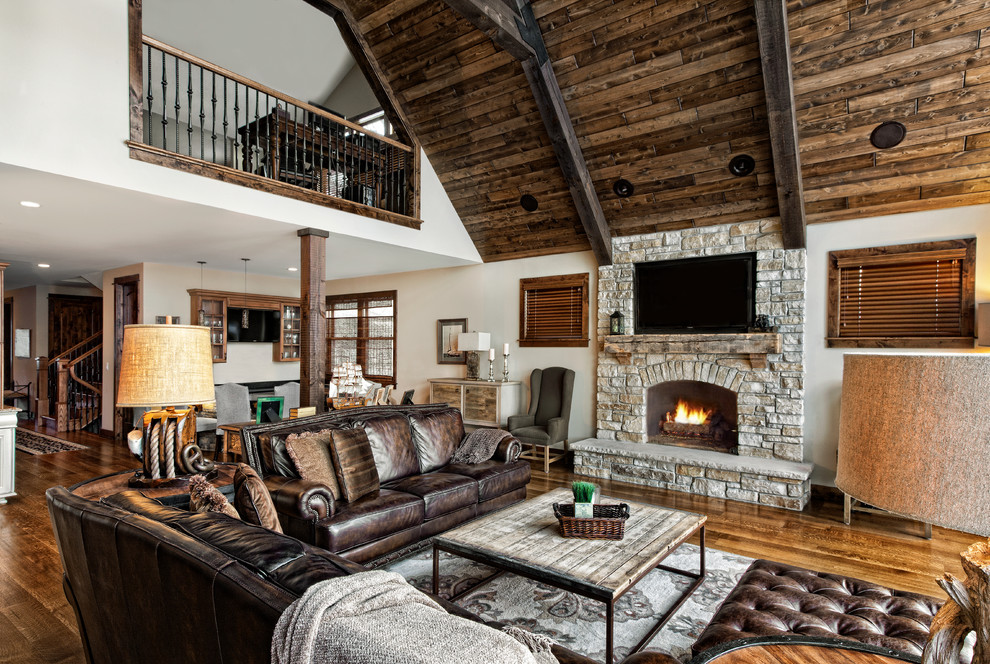 This is an example of a traditional open plan living room in Chicago with a standard fireplace, a stone fireplace surround, a wall mounted tv and feature lighting.